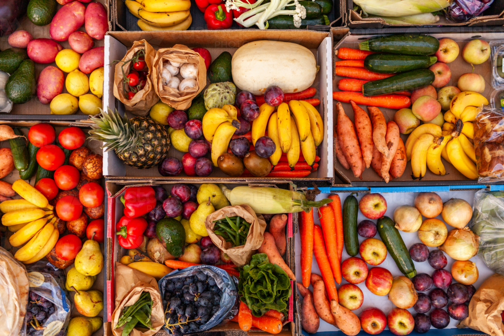 Colourful overhead angle of fresh organic fruit and vegetable boxes at unsupermarket food hub - Australian Stock Image