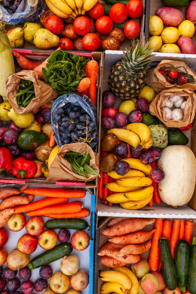 Colourful overhead angle of fresh organic fruit and vegetable boxes at unsupermarket food hub - Australian Stock Image
