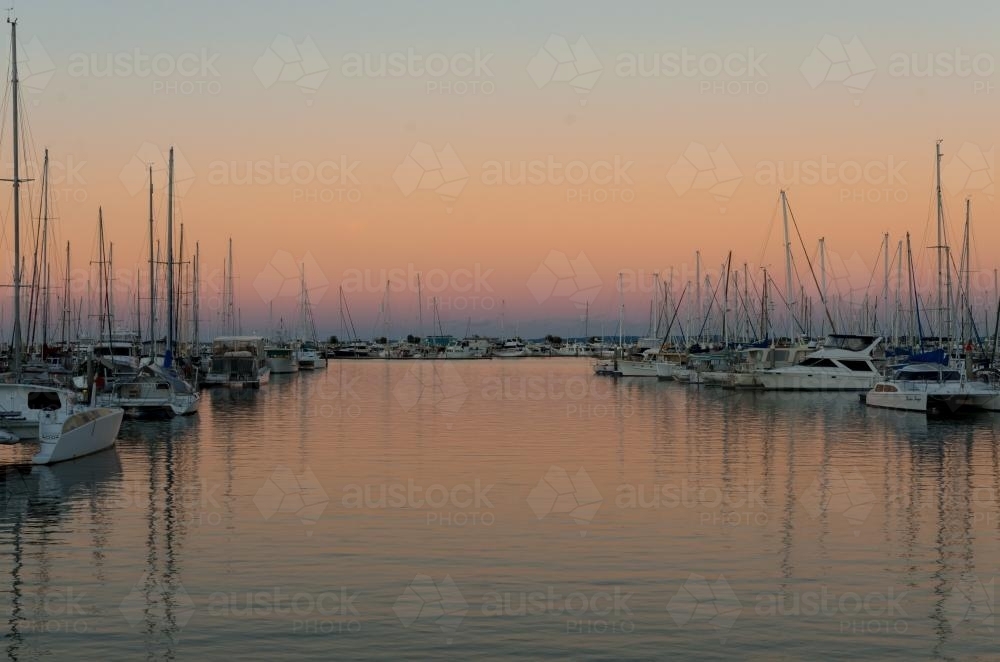 Colourful sunset reflections in a marina with yachts and boats. - Australian Stock Image