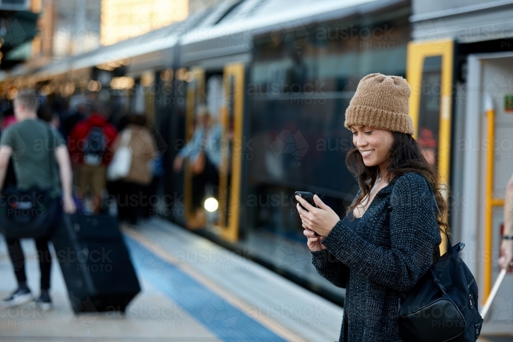 Commuter coming off train at station using mobile phone - Australian Stock Image