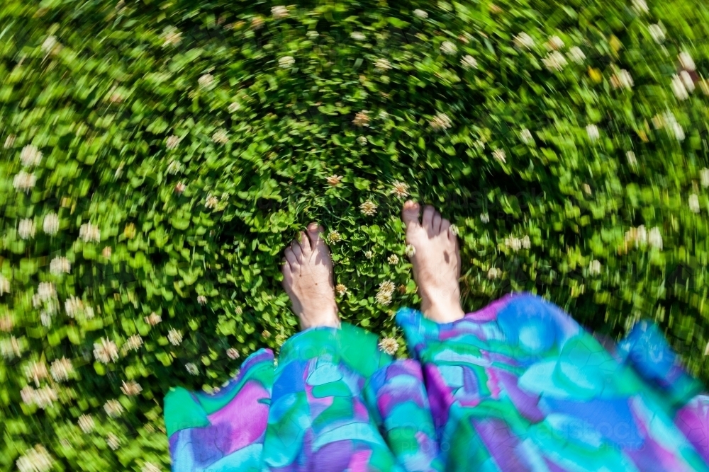 Concept - vertigo, imbalance, dizziness. Spinning photo of bare feet standing on clover lawn - Australian Stock Image