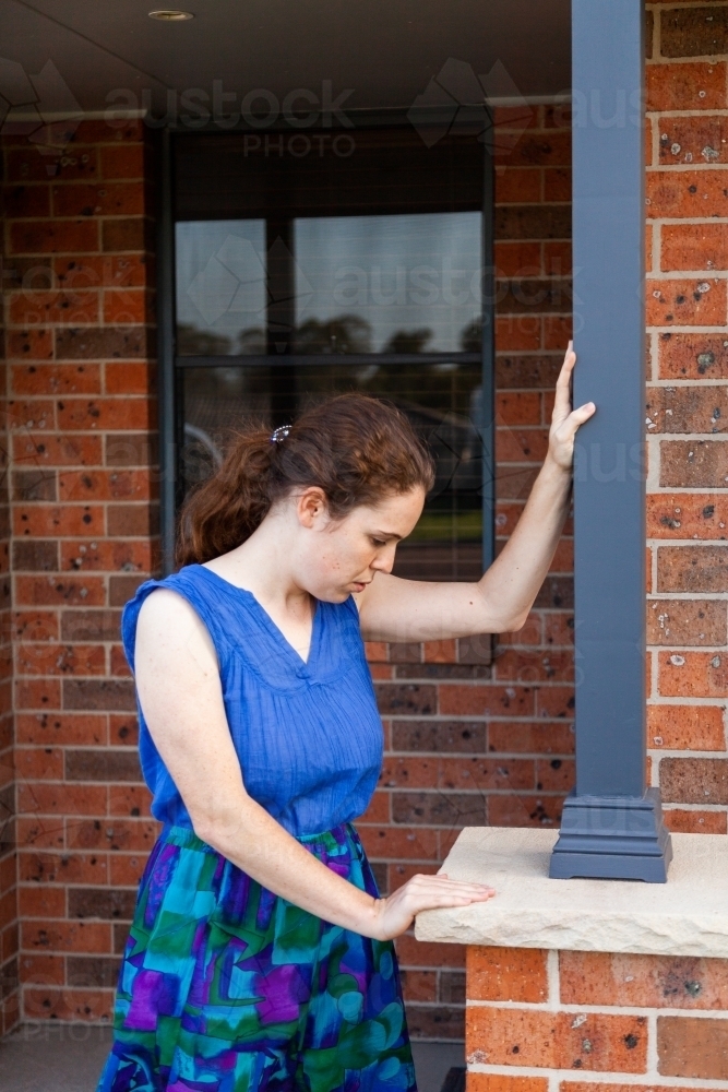 Concept - vertigo, spinning, dizziness. Woman leaning on post outside home to stay upright - Australian Stock Image
