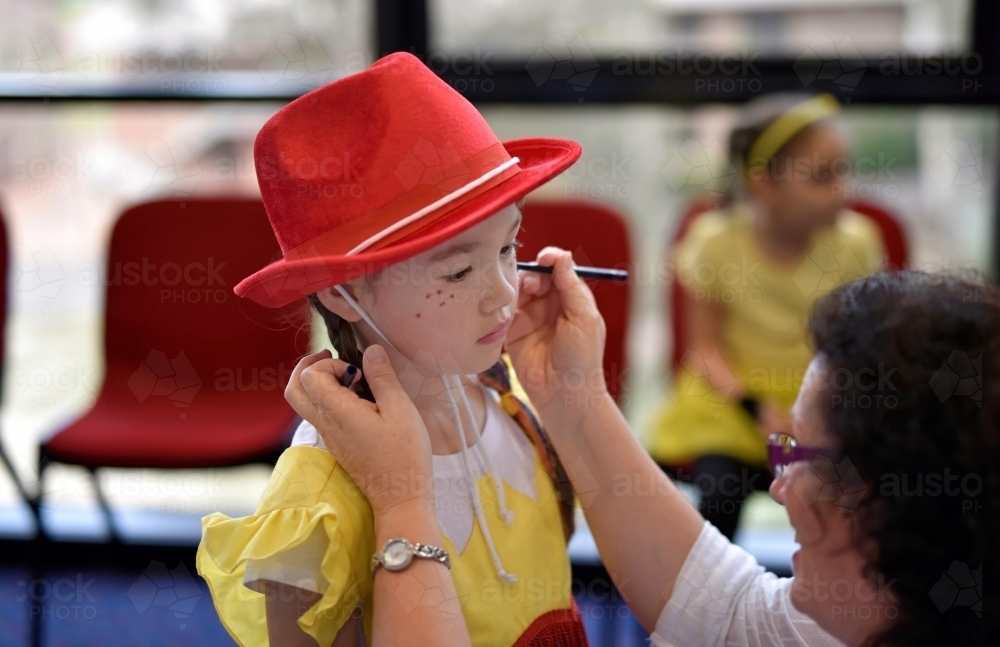 Concert Rehearsal for a school play putting the finishing touches on a young girl's face - Australian Stock Image