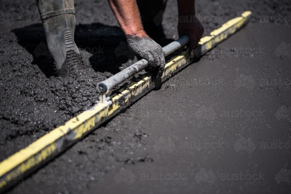 Concreter screeding black concrete - Australian Stock Image
