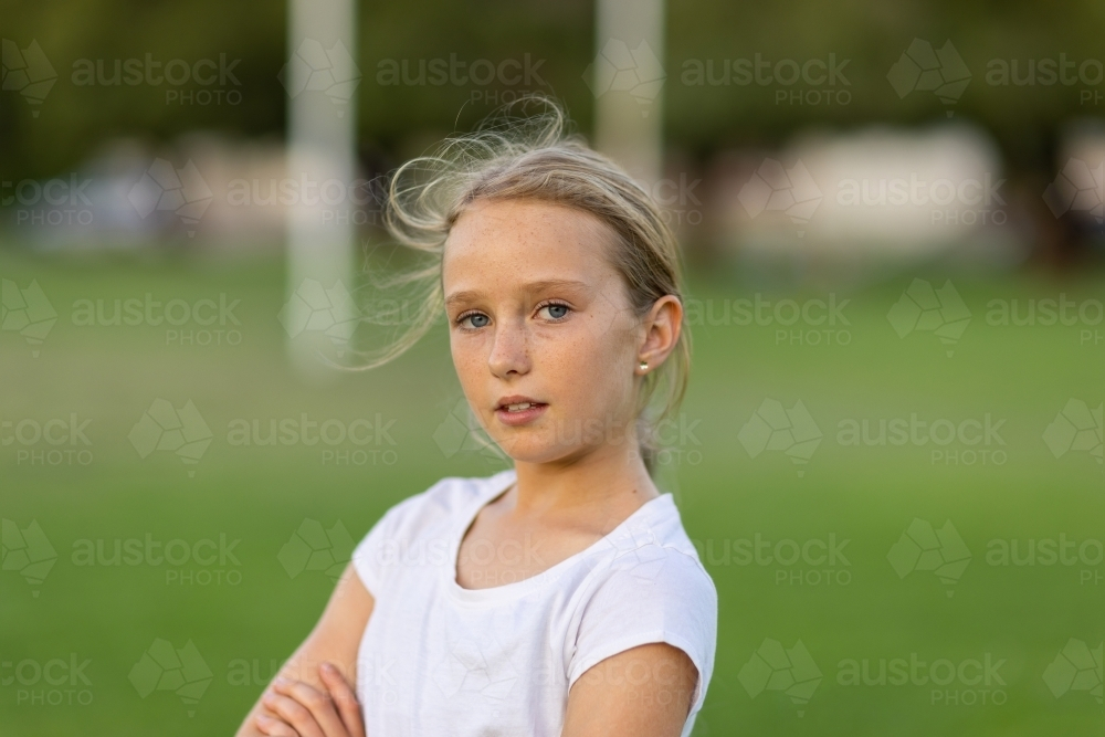 confident 10 year old girl wearing white tee shirt with blurry background - Australian Stock Image