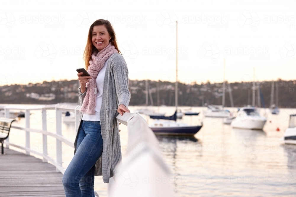Confident woman using mobile phone on wharf - Australian Stock Image