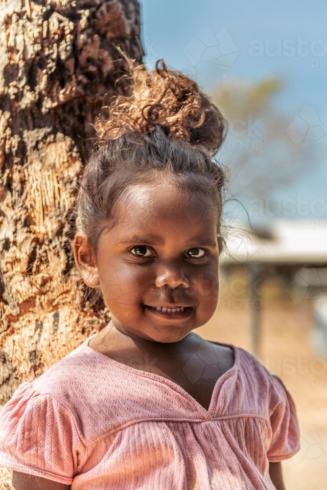 Aboriginal 3 year old girl by tree - Australian Stock Image
