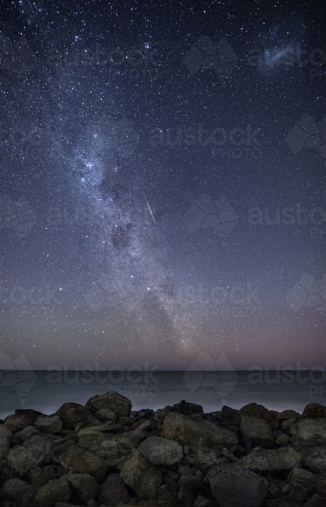 Constellation over ocean with rocks in foreground. - Australian Stock Image