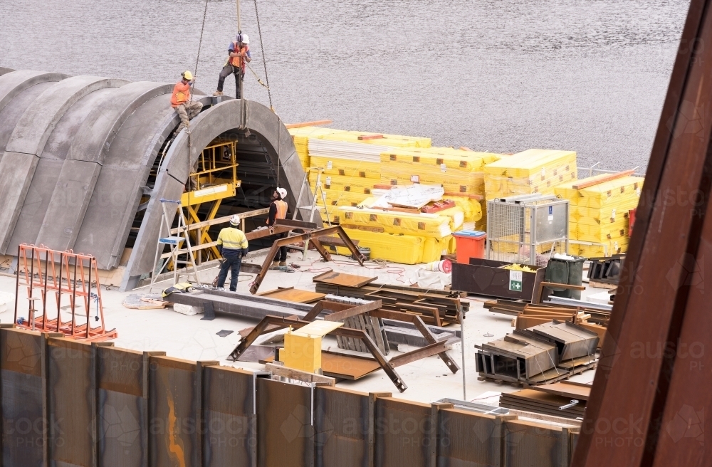 Construction of a building extension on the side of a river - Australian Stock Image