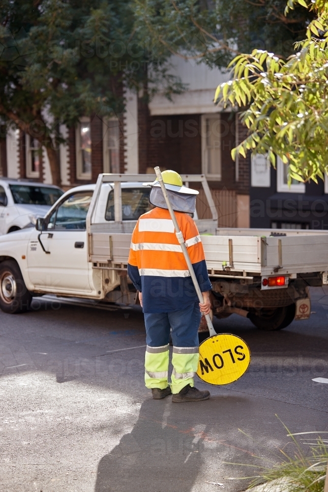 Construction worker holding slow sign whilst ute passes by - Australian Stock Image