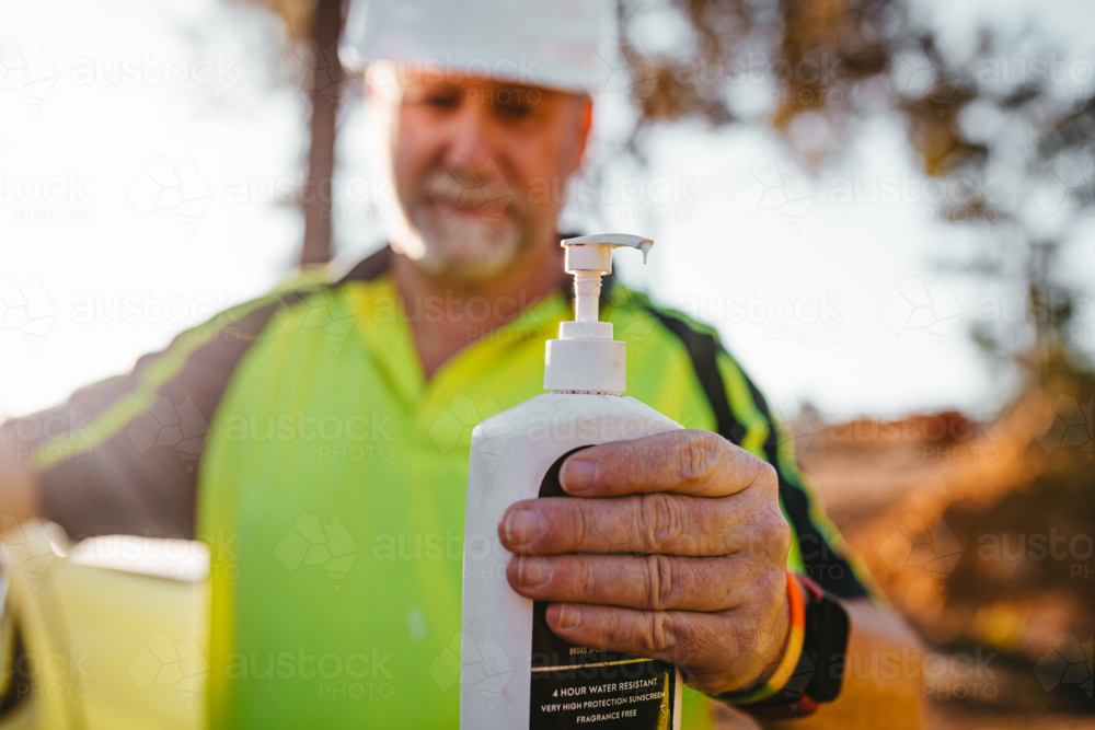 Using Sunscreen Workman Image of Construction worker on a blurry background holding a sunscreen ...