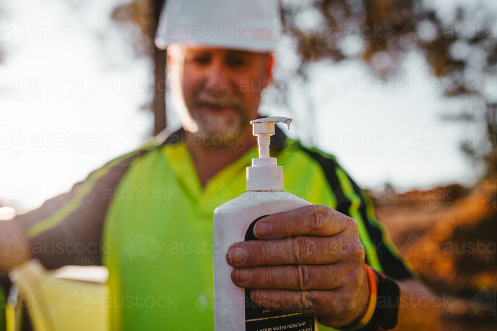 Image of Construction worker on a blurry background holding sunscreen ...