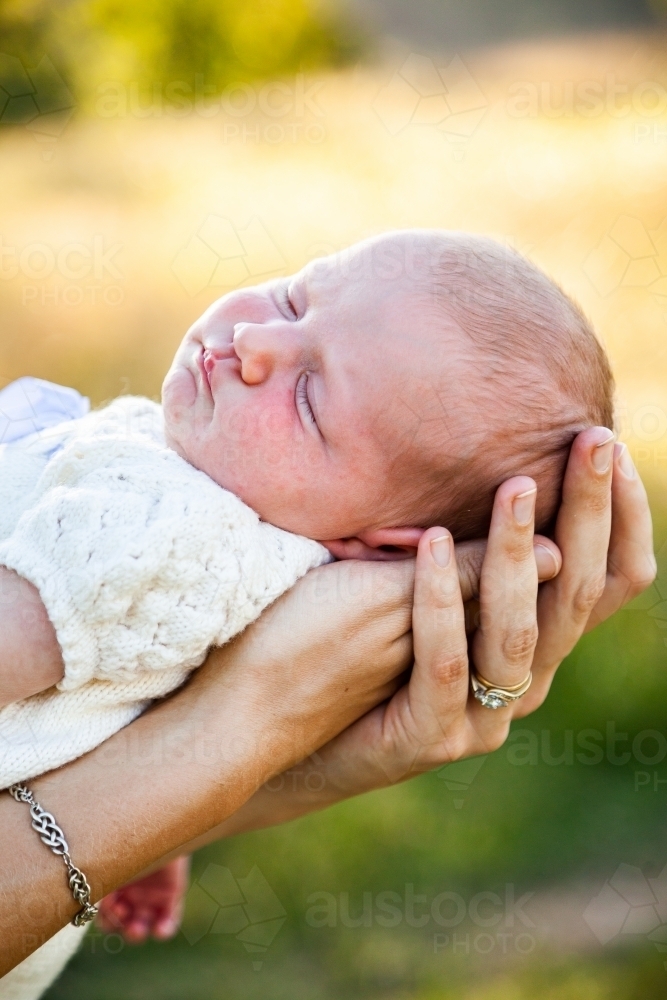 Content sleepy baby in mothers arms - Australian Stock Image