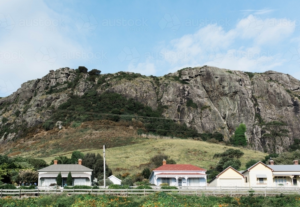 Continuous wooden fence in front of houses with rocky mountain in background - Australian Stock Image