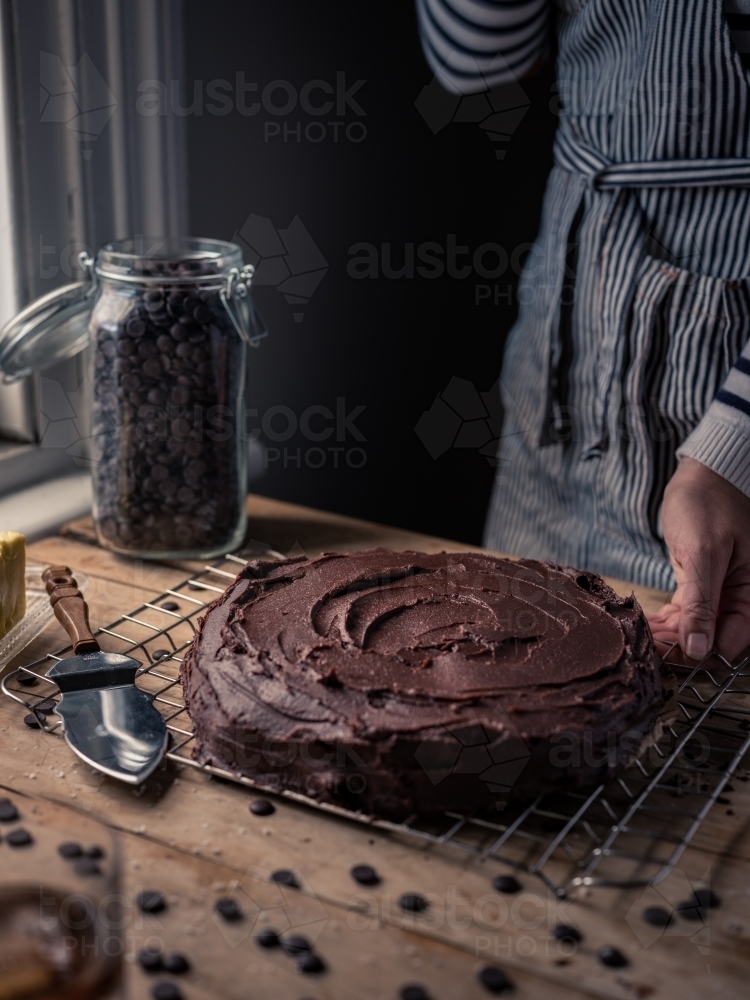 Cook standing behind a chocolate cake that has just been iced - Australian Stock Image