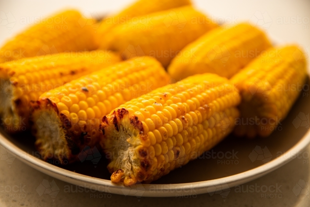 Image of cooked cobs of corn on a plate ready to eat - Austockphoto