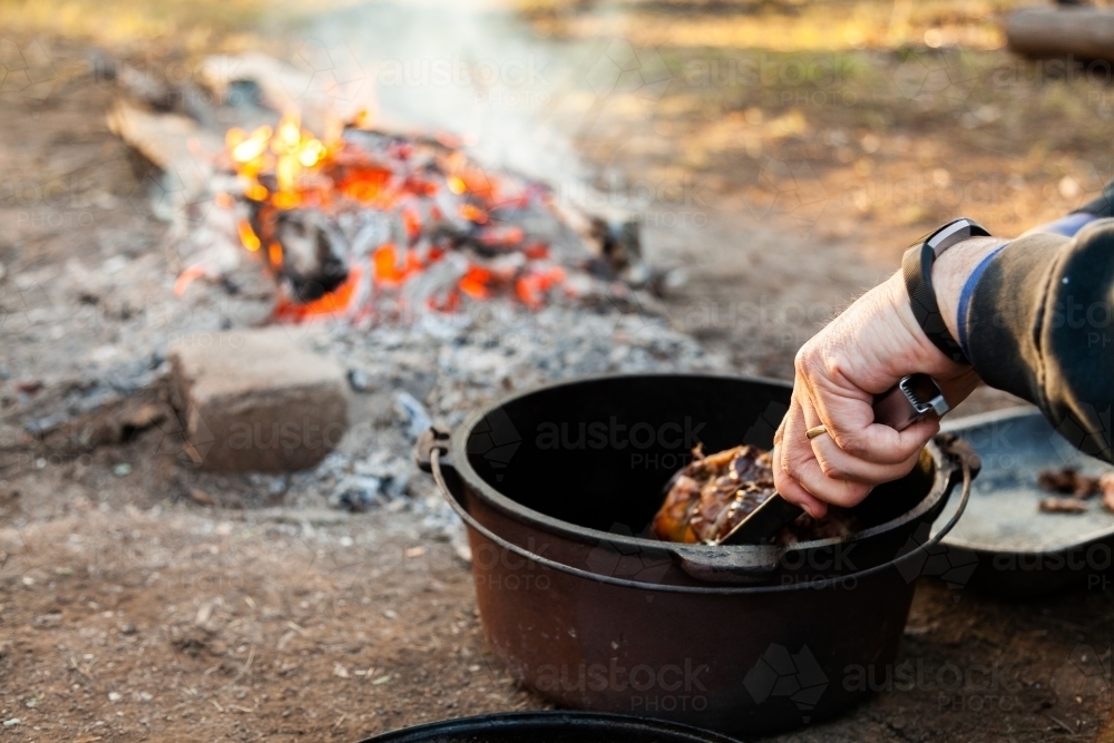 Cooking food in camp oven over campfire in winter - Australian Stock Image