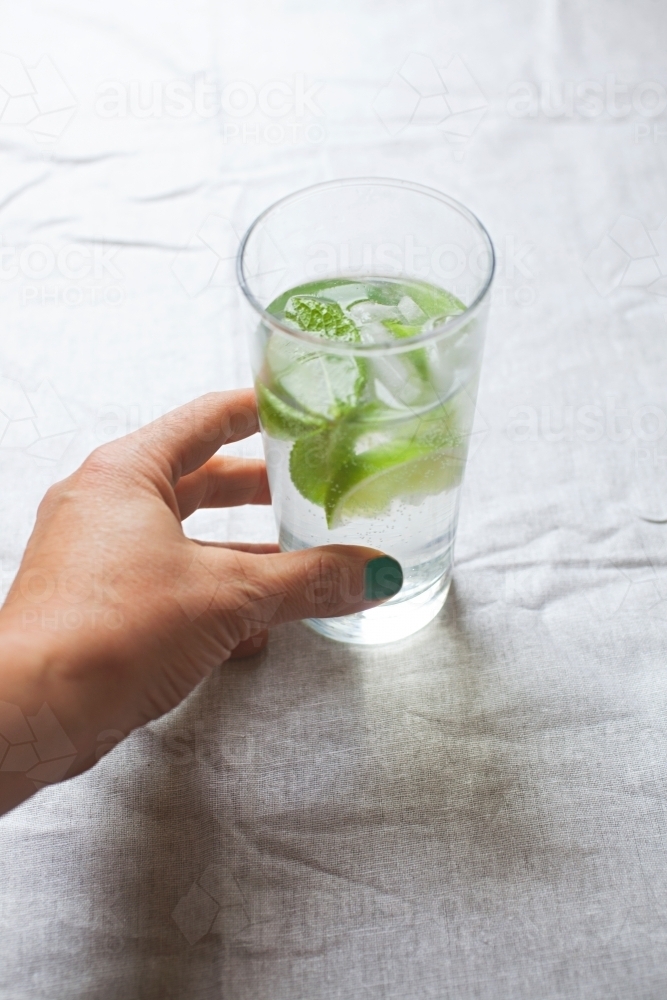 Cool glass of water with ice and mint on tabletop - Australian Stock Image