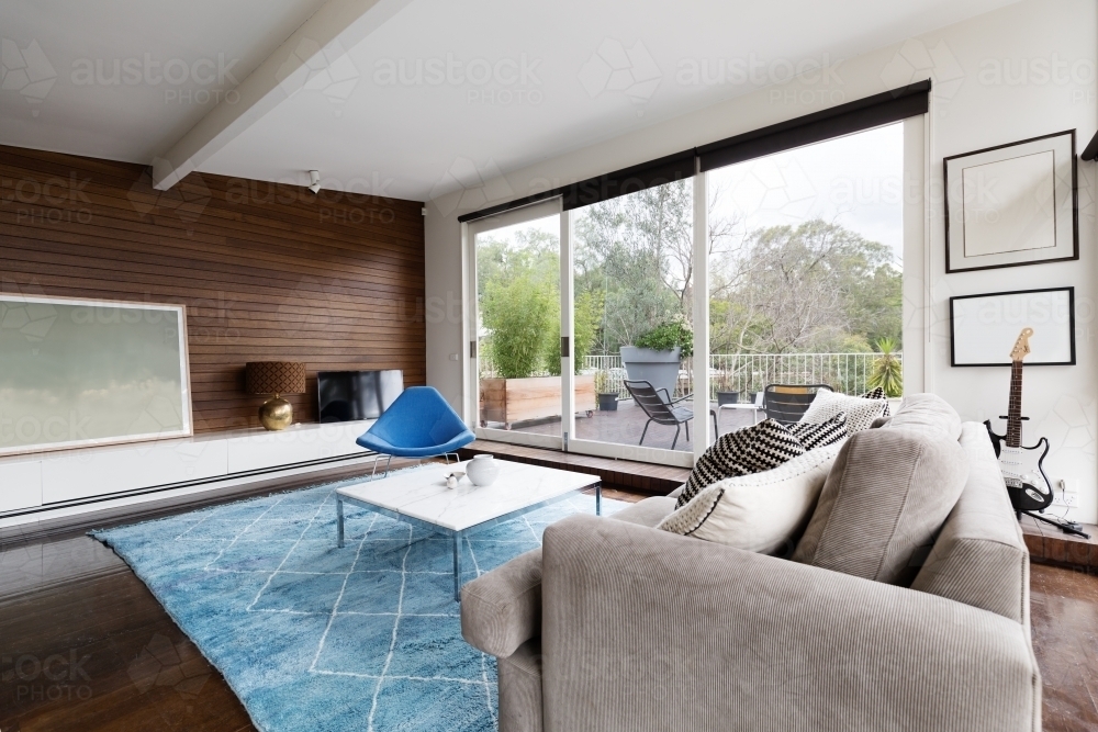 Cool mid century modern lounge with outlook to terrace - Australian Stock Image