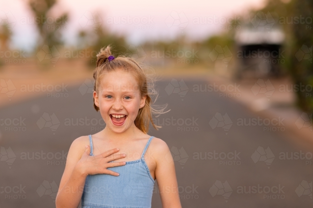 coquettish little blonde girl outside with wind in hair and smile on face - Australian Stock Image