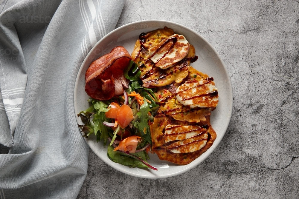 Corn frittata topped with mozzarella cheese with vegetable salad and bacon on the side. - Australian Stock Image
