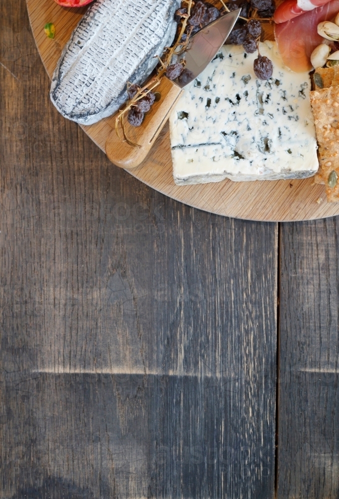 Corner of cheese platter on wooden table - Australian Stock Image