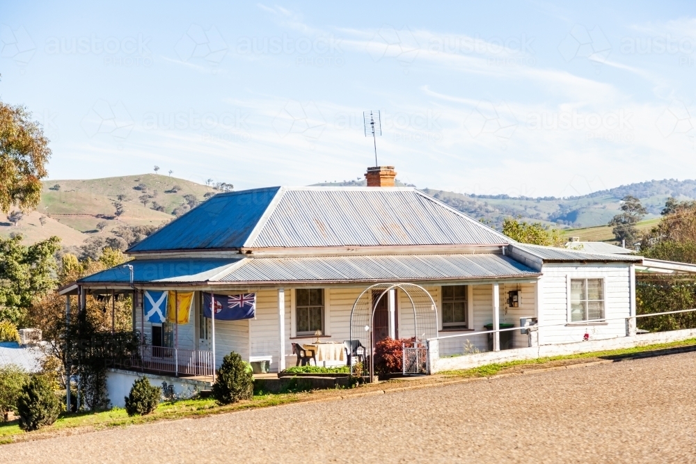 Cottage with flag of New South Wales beside road - Australian Stock Image