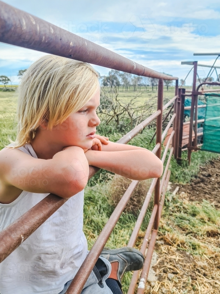 Country boy leaning on stock yard fence on farm - Australian Stock Image