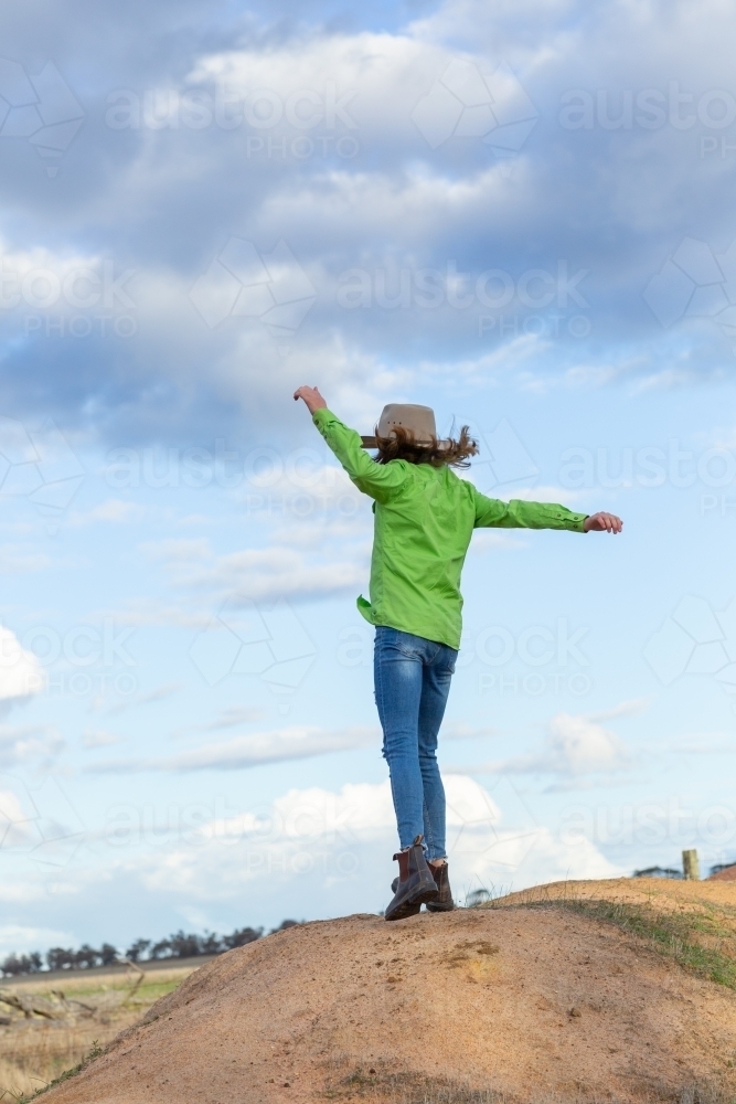 Country girl happily twirling with arms in the air from behind - Australian Stock Image