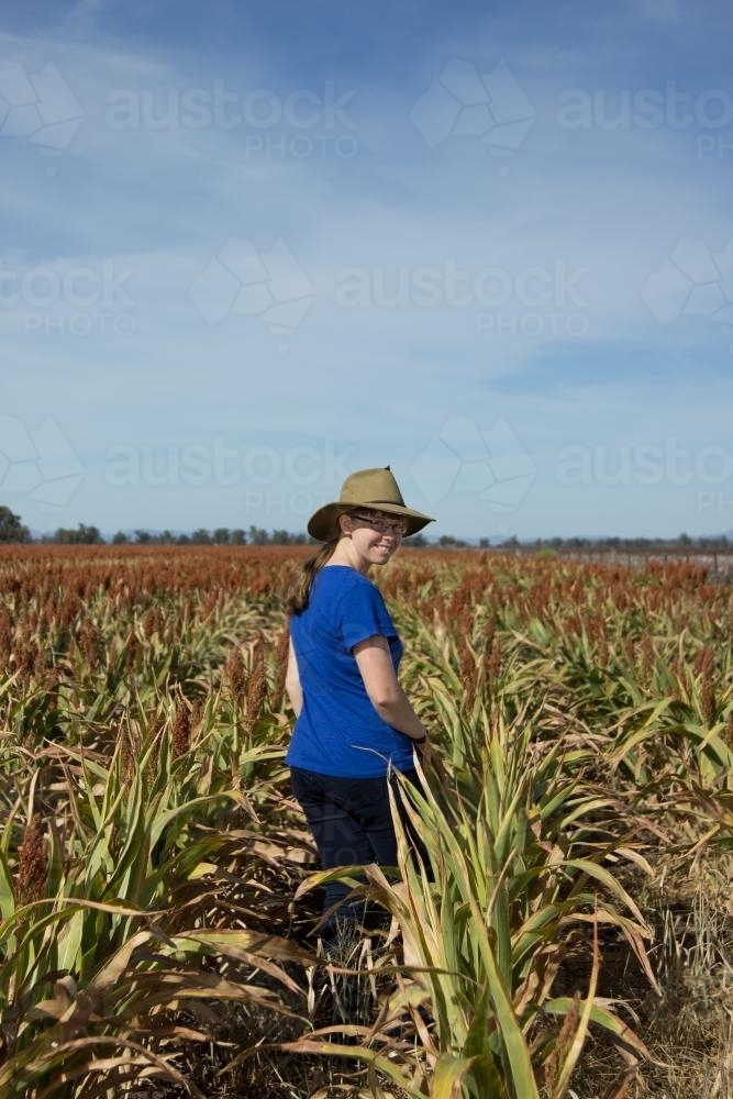 Country kid standing in a sorghum crop looking back at camera - Australian Stock Image