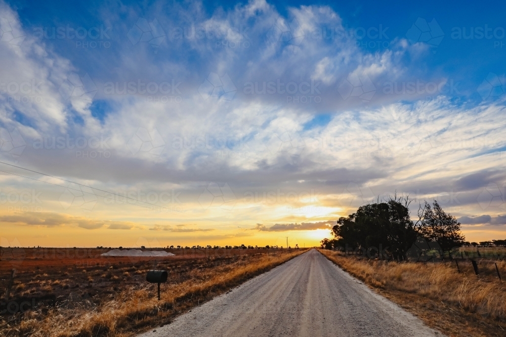 Country lane at sunset with gypsum pile in empty paddock - Australian Stock Image