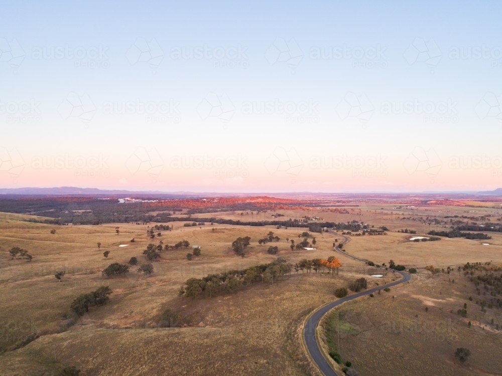 Country road winding away over hills at sunset - Australian Stock Image