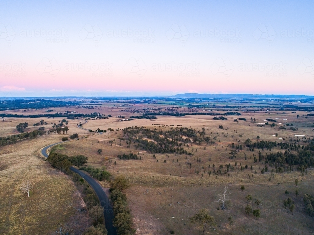 Country road winding away over hills at sunset - Australian Stock Image