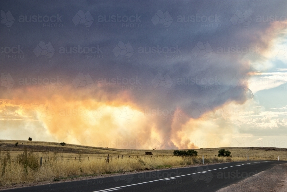 Country road with sun shining through billowing smoke - Australian Stock Image