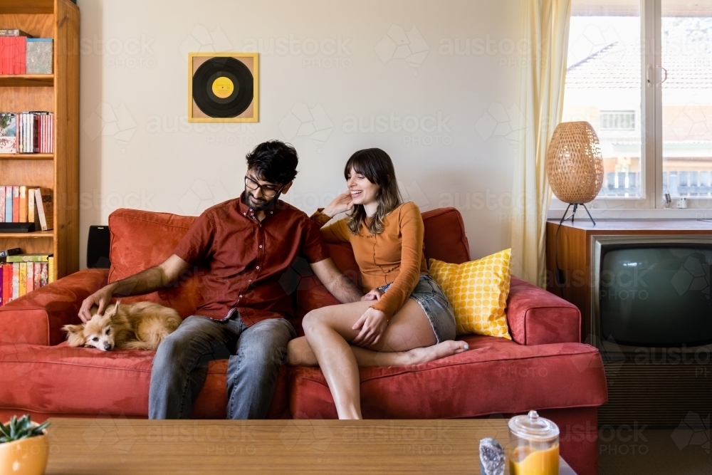 couple at home in living room with dog on sofa - Australian Stock Image