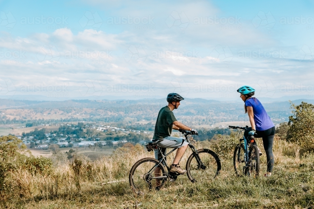 Couple at top of mountain on mountain bikes - Australian Stock Image