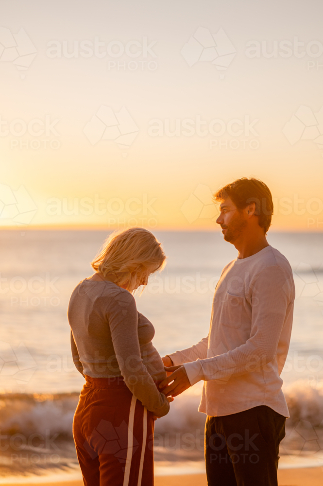 Couple celebrating pregnancy at Manly Beach during sunrise - Australian Stock Image