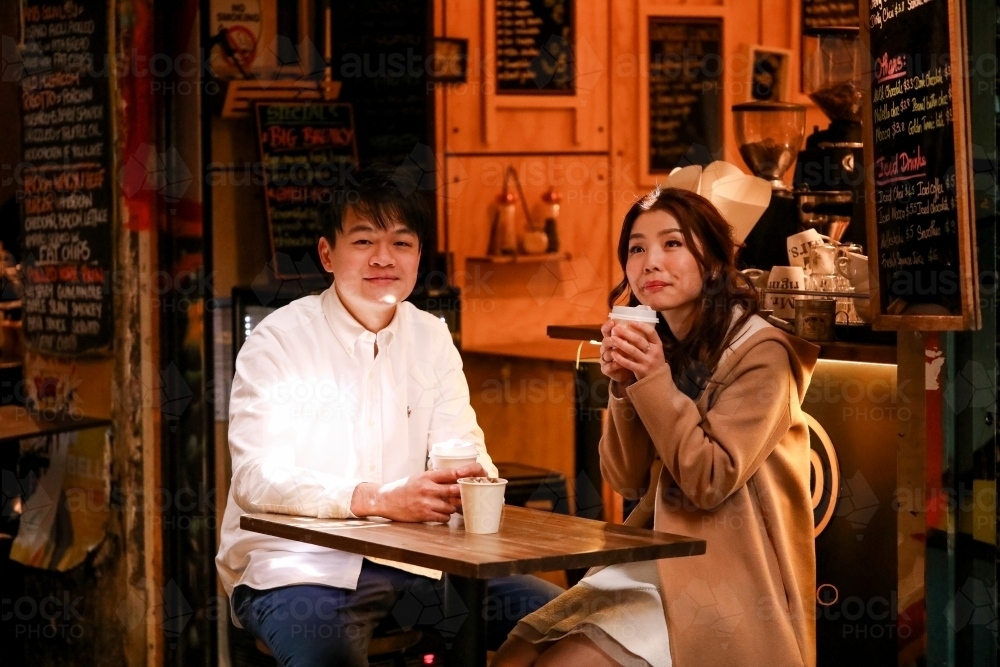 Couple enjoying coffee together at alfresco table at small coffee shop in Melbourne laneway - Australian Stock Image