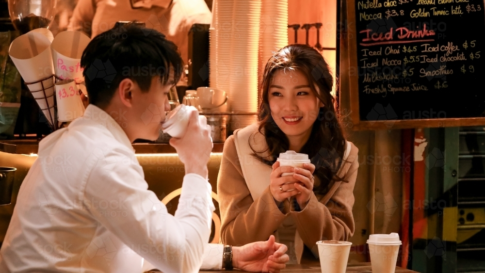 Couple enjoying coffee together at alfresco table at small coffee shop in Melbourne laneway - Australian Stock Image