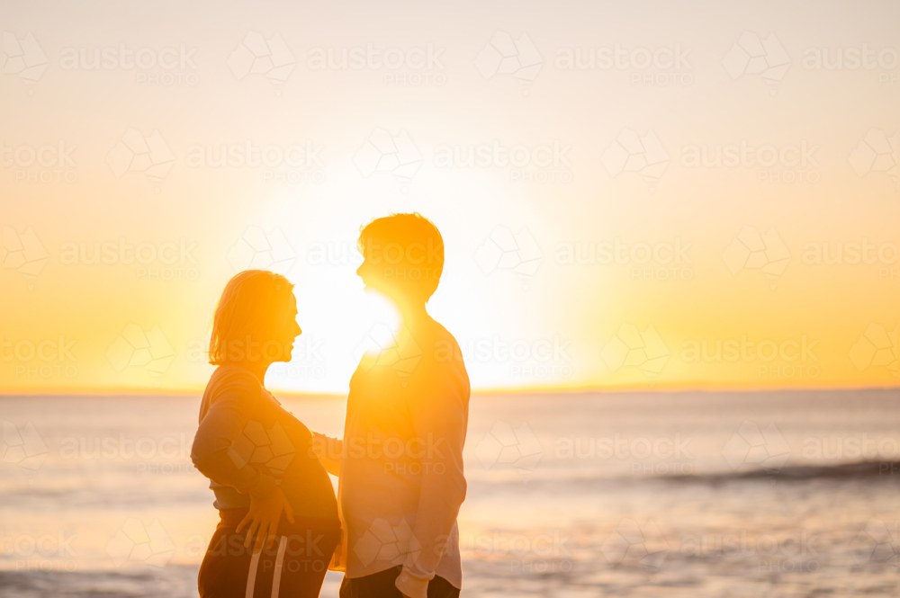 Couple enjoying sunrise at Manly Beach during pregnancy - Australian Stock Image