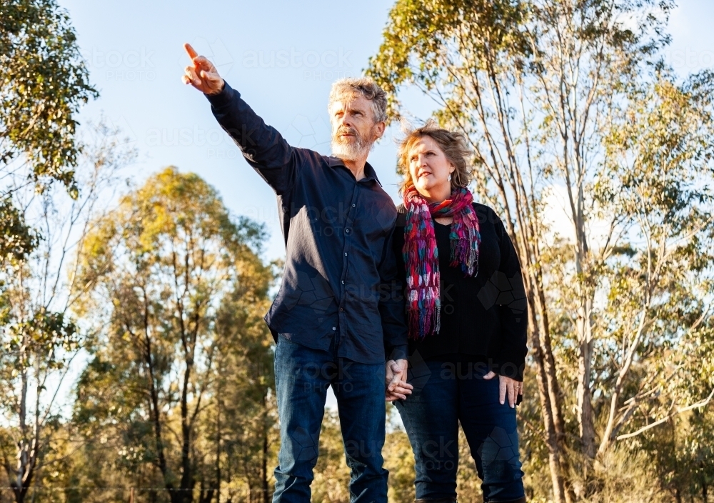 Couple holding hands man pointing into distance - Australian Stock Image
