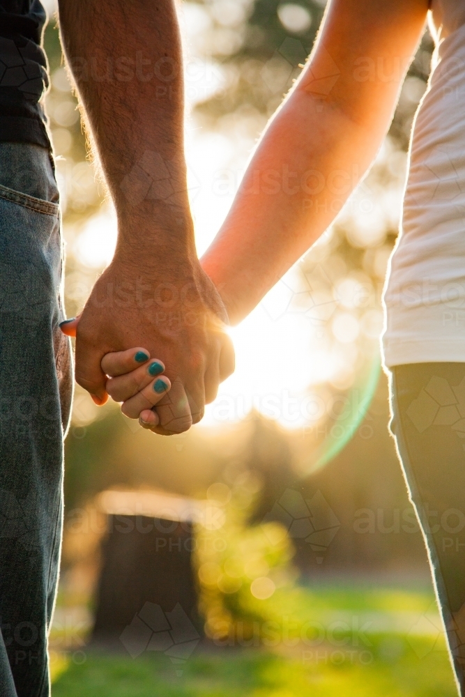Couple holding hands with sunlight shining through - Australian Stock Image