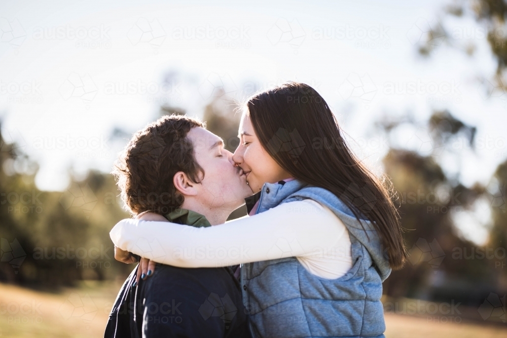 Couple kissing with woman's arms around man's neck - Australian Stock Image