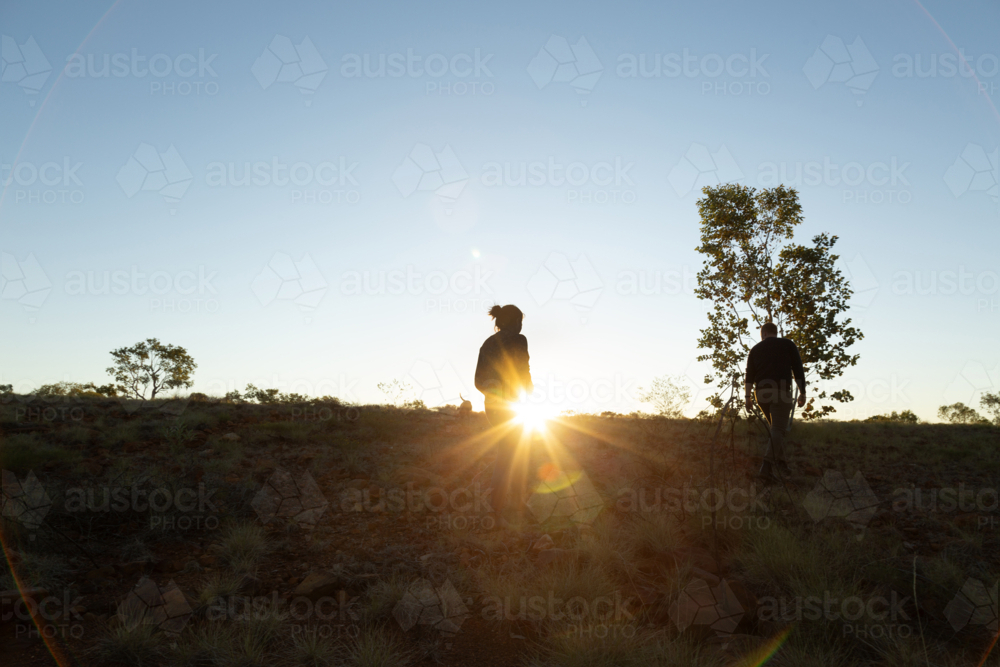 Couple on sunset walk through country paddock landscape - Australian Stock Image