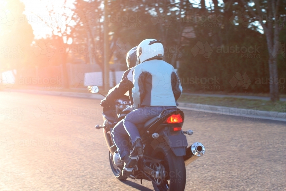 Couple riding a motorbike on a suburban street - Australian Stock Image