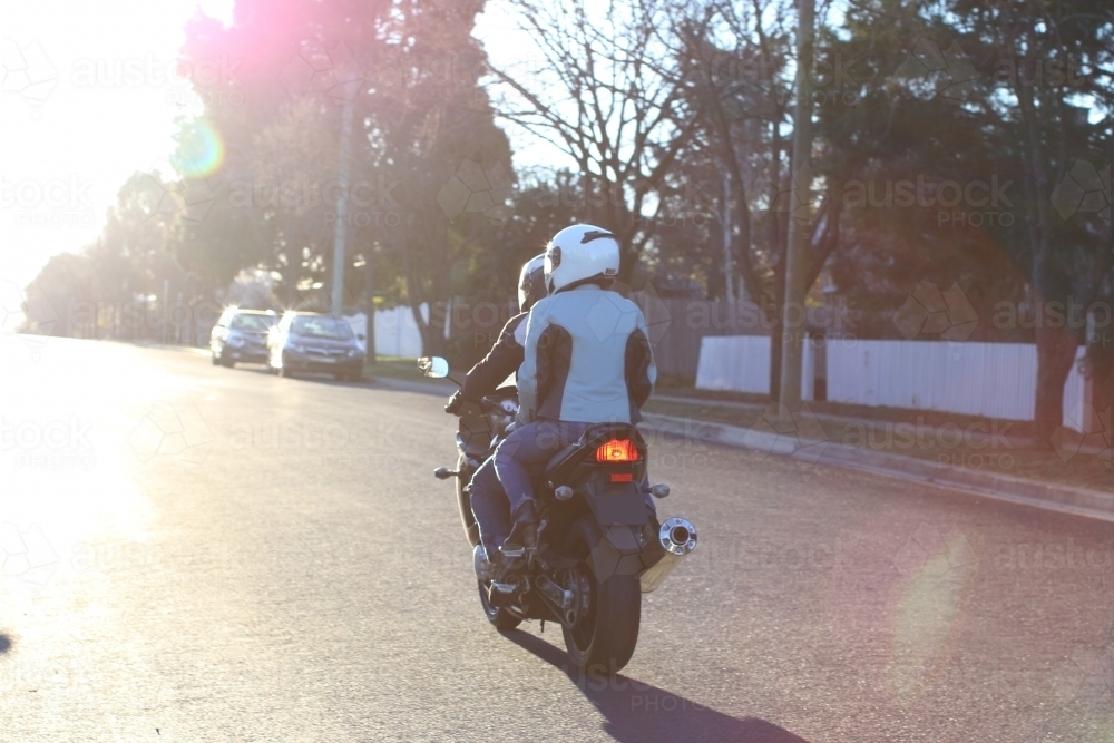Couple riding a motorbike on a suburban street - Australian Stock Image