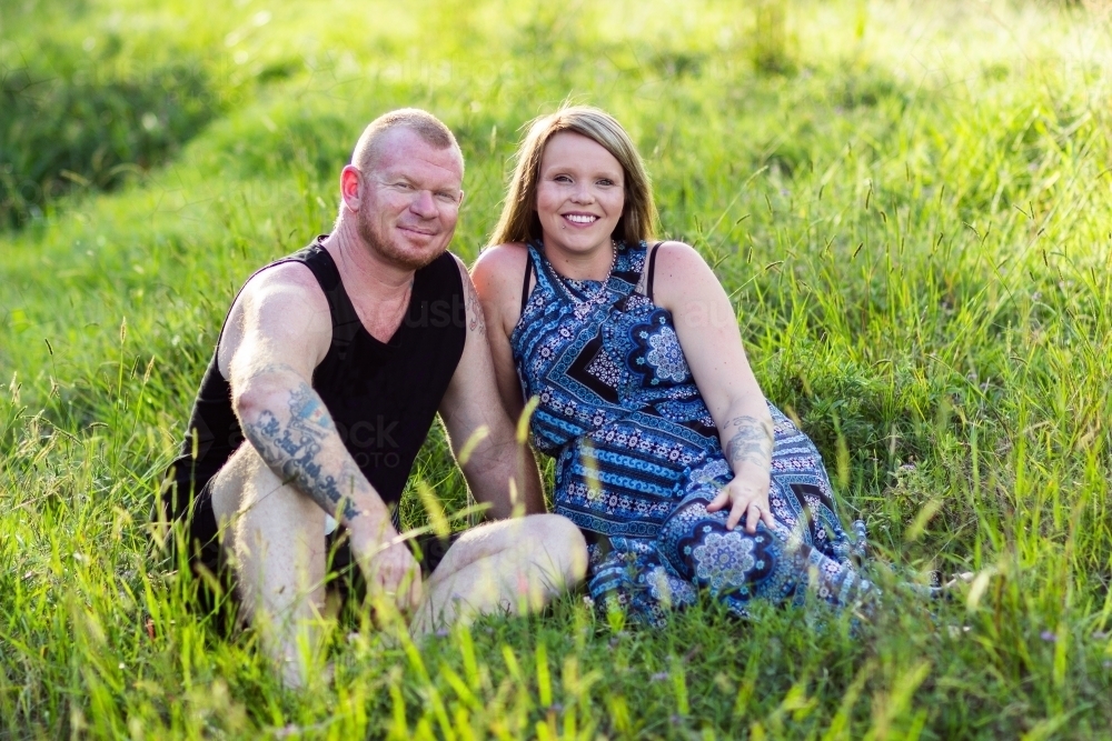 Couple seated together on green grass - Australian Stock Image