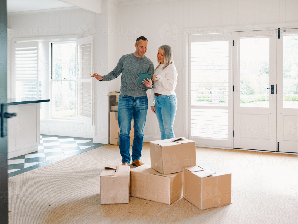 Couple standing behind boxes in an empty space of their new home planning - Australian Stock Image