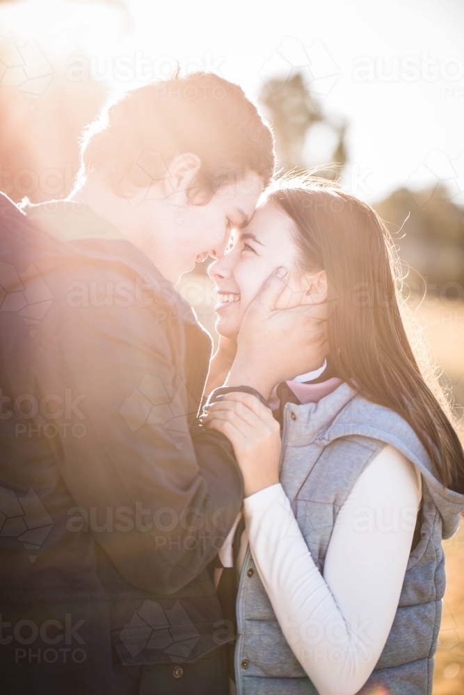 Couple standing close foreheads together man holding girlfriends face smiling - Australian Stock Image