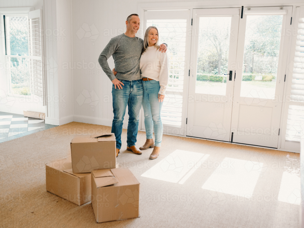 Couple standing in new home with boxes - Australian Stock Image